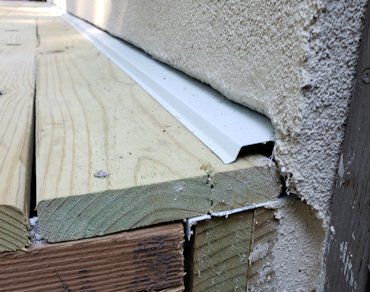 showing the drainage gap over the flashing and between the floorboards