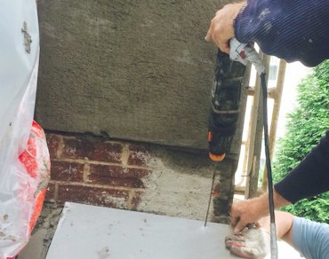 Flagstone is drilled with a hammer drill for the bolts