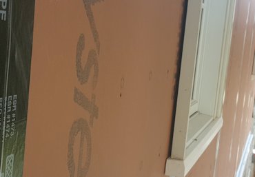 A space is left behind the window trim to allow for the thickness of the drainage mat