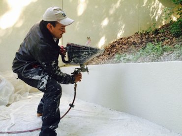 White portland and sand is sprayed with a hopper gun