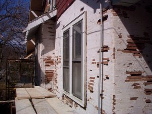 Old stucco is stripped off down to the old wood lath